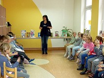 Dzieci słuchają bibliotekarki, która opowiada o poezji, wyobraźni i rymach