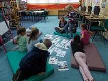 Dziewczynka trzyma w ręku zapisana nazwę zawodu i kładzie na odpowiednim obrazku